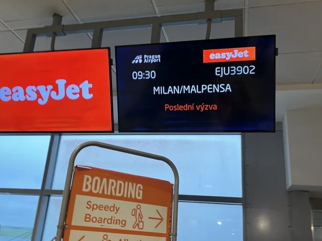 Obrazovka u nástupní brány v Praze s poslední výzvou k letu easyJet do Milána Malpensy