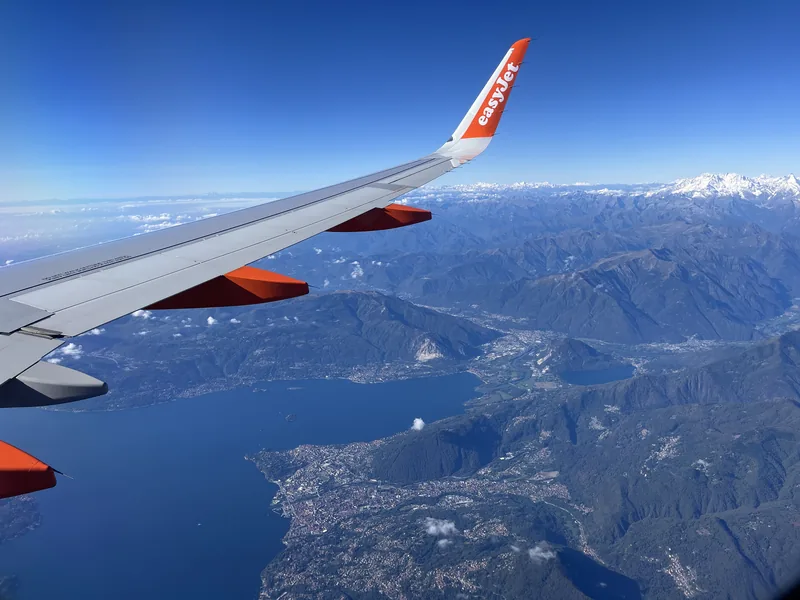 Křídlo letadla easyJet nad jezerem a horskou krajinou