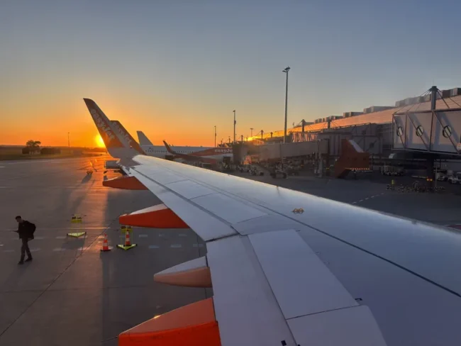 Křídlo letadla easyJet na letišti při západu slunce