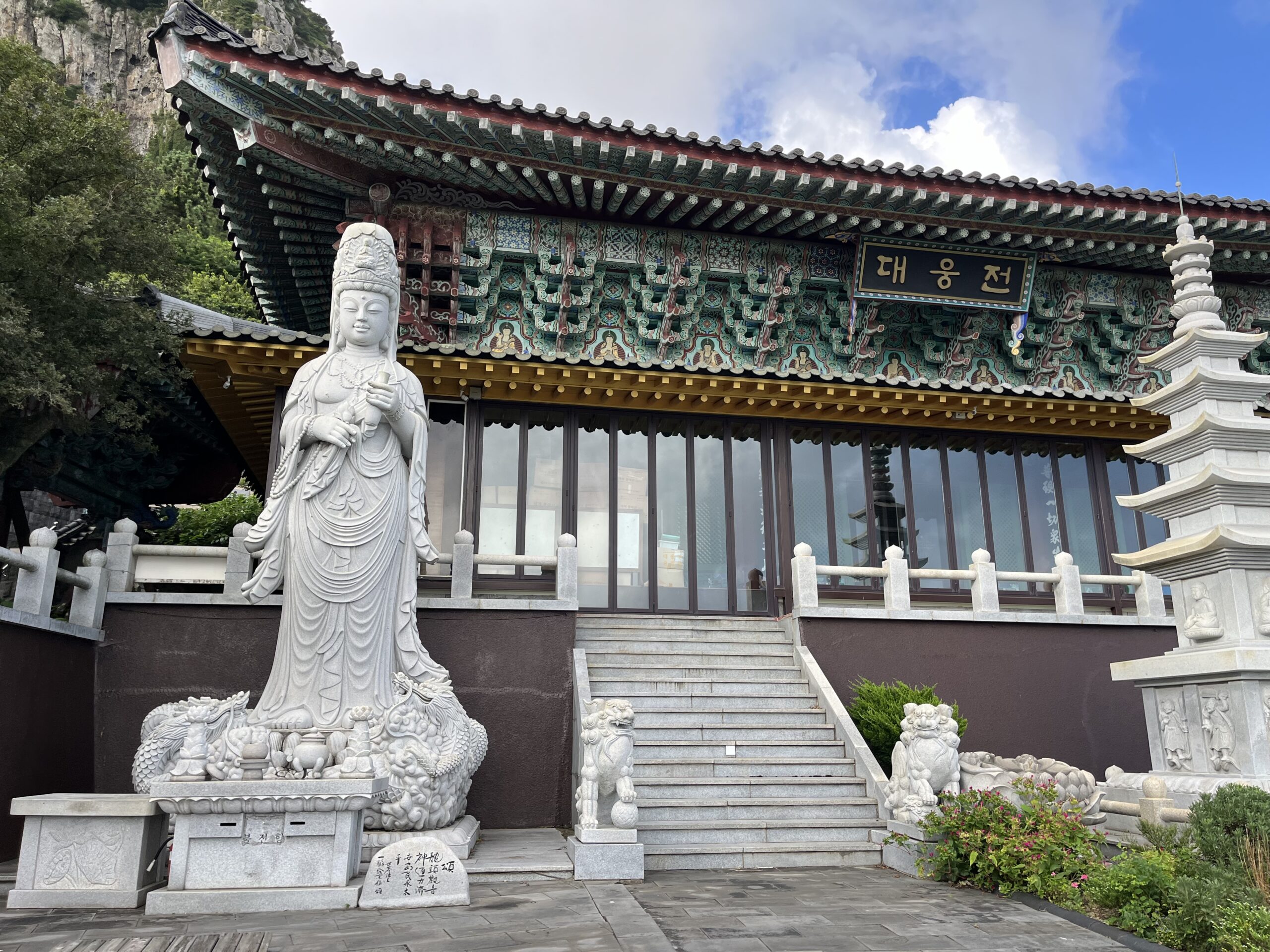 Zdobený buddhistický chrám s kamennou sochou pod horou Sanbangsan na Jeju
