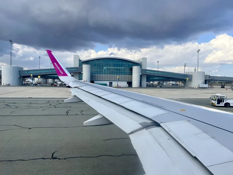 Pohľad cez krídlo lietadla Wizz Air na letiskový terminál
