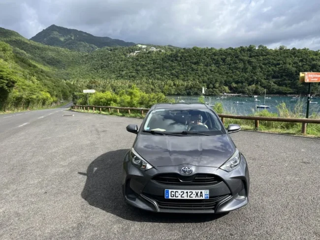 Our rental car parked beside green mountains in Guadeloupe