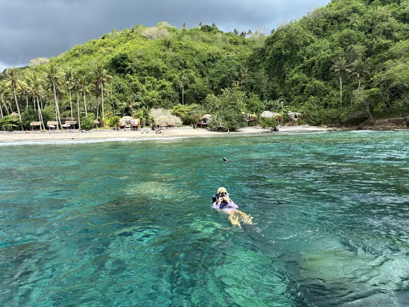 Koupání v průzračném moři u pláže s palmami na Bali