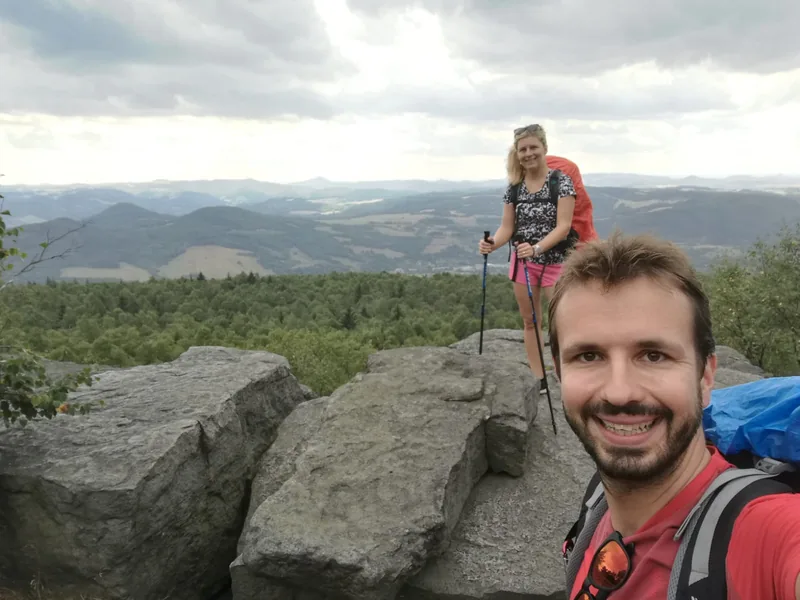 Společná fotografie z túry na skalní vyhlídce, v pozadí turistka s holemi